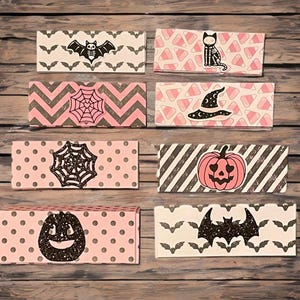 May include: A collection of eight Halloween-themed gift boxes. Each box features a different design, including bats, spiderwebs, pumpkins, and a witch's hat. The boxes are decorated with pink, black, and white patterns, perfect for spooky season.