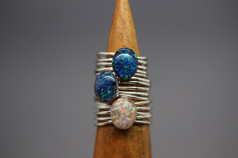 Op de afbeelding: Drie zilveren ringen met opaalstenen. De stenen zijn blauw, groen en wit met iriserende glitter.