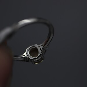 May include: A silver ring with a clear oval-shaped gemstone surrounded by smaller clear gemstones.