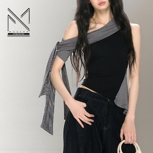 May include: Black asymmetrical top with grey striped detailing and a single sleeve with a bow. The top features the text "MODERN FITBYPETER" in the upper left corner. The top is paired with dark wash denim.