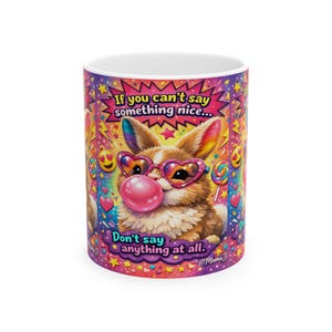 May include: A white ceramic mug with a colorful design featuring a cartoon rabbit wearing heart-shaped sunglasses and blowing a bubble. The mug has text that reads "If you can't say something nice... Don't say anything at all."