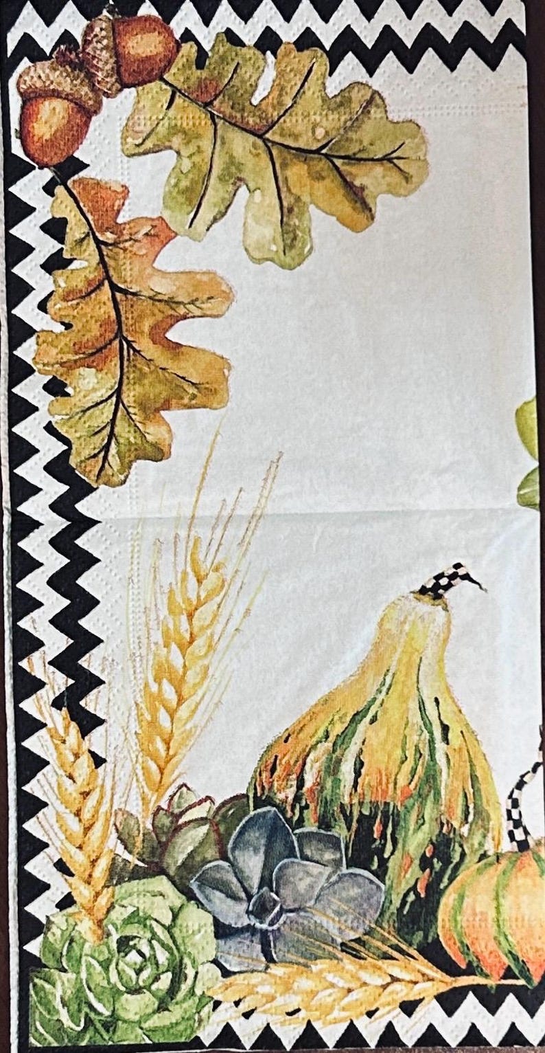 May include: A paper napkin featuring a black and white chevron border. The design includes watercolor illustrations of brown acorns, green and yellow oak leaves, golden wheat stalks, green succulents, and two gourds with black and white checkered stems.