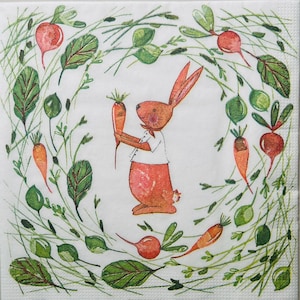 May include: Square paper napkin with a watercolor illustration of a reddish-orange bunny holding two carrots. The bunny is wearing a white shirt and red pants. The bunny is surrounded by a wreath of green leaves, carrots, and red radishes.