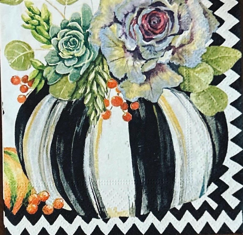 May include: A square paper napkin featuring a central pumpkin with vertical black and white stripes. The pumpkin is topped with a watercolor-style arrangement of green succulents, light blue cabbage-like flowers, and small orange berries.