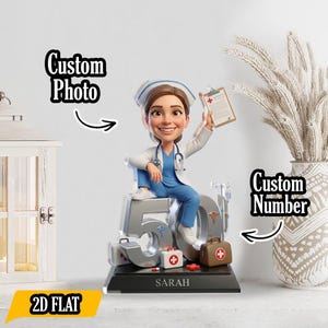 May include: A figurine of a smiling nurse in blue scrubs and a white coat, holding a clipboard, sits atop a large silver "50". The base includes a medical bag, first aid kit, and the name "SARAH". The words "Custom Photo", "Custom Number", and "2D FLAT" are also visible.