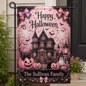 Könnte beinhalten: Eine rechteckige Gartenflagge mit einem Halloween-Motiv in Pink und Schwarz, das ein Spukhaus, Geister, Kürbisse und eine schwarze Katze zeigt. Der Text lautet Happy Halloween und The Sullivan Family. Das Design enthält rosa Schleifen und Sterne.