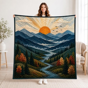 May include: A rectangular quilt featuring a landscape scene with a bright orange sun rising over blue mountain ranges. A winding river flows through a valley filled with green and orange pine trees under a sky with clouds and flying birds.