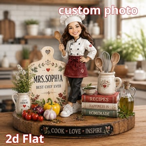 May include: A custom figurine of a chef wearing a white hat, white jacket, and maroon apron, standing on a wooden base with a cutting board labeled MRS. SOPHIA BEST CHEF EVER, a stack of books labeled RECIPES, HAPPINESS IS, and HOMEMADE, and a sign reading COOK LOVE INSPIRE.
