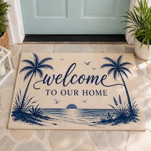 May include: A rectangular beige doormat featuring a dark blue graphic of a beach scene with two palm trees, a setting sun over the ocean, and birds in flight. The text "welcome TO OUR HOME" is printed in a dark blue script and block font.