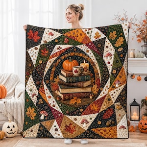 Puede incluir: Una colcha rectangular con un diseño circular central de una calabaza, una vela encendida y una pila de libros rodeados de hojas de otoño. La colcha está decorada con patrones de setas, bellotas y hojas de arce en tonos naranja, verde y marrón, acentuada con pequeños botones marrones por toda la tela.