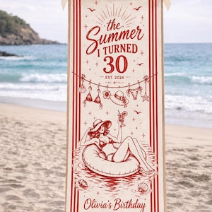 May include: A vertical off-white fabric banner with red ink illustrations and text. The banner features the text "the Summer I TURNED 30 EST. 2026" and "Olivia's Birthday LAKE TAHOE, CA". It depicts a person in a pool float and beach items.