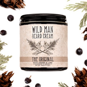 Wild Man Beard Cream in The Original scent shown in a 4oz amber glass jar. Cedar, fir cones and juniper berries surround.