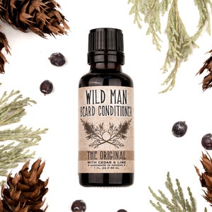 Wild Man Beard Conditioner in The Original scent shown in a 30ml amber glass bottle. Cedar, fir cones and juniper berries surround.