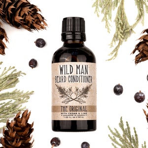 Wild Man Beard Conditioner in The Original scent shown in a 50ml amber glass bottle. Cedar, fir cones and juniper berries surround.