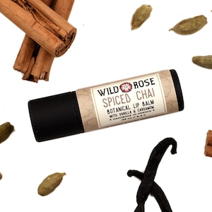 Spiced Chai Natural Lip Balm in a biodegradable paper tube. Cinnamon stick, cardamom and vanilla pods surround.