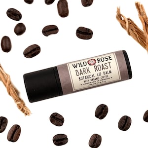 Dark Roast Lip Balm in a biodegradable paper tube. Coffee beans and vetiver root surround.
