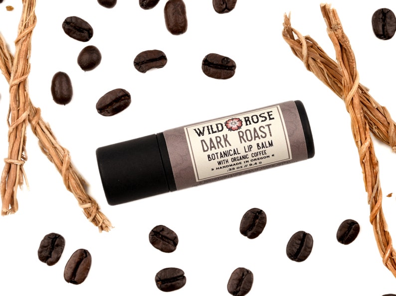 Dark Roast Lip Balm in a biodegradable paper tube. Coffee beans and vetiver root surround.