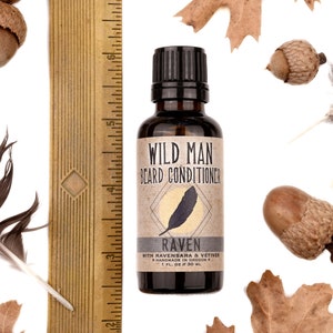 Wild Man Beard Oil Conditioner - Raven scent in 30ml amber glass bottle. Shown next to ruler at about 3.75" tall. Black feathers, acorns and dried oak leaves surround.