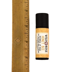 Wild Rose Botanical Lip Balm in a biodegradable paper tube shown next to ruler at about 3" tall.