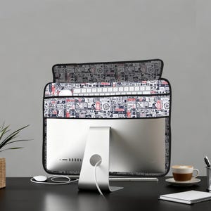 Peut inclure: Un écran d'ordinateur avec une housse à motifs noirs, blancs et rouges. La housse recouvre l'écran et le clavier. Une souris blanche et une tasse de café sont sur le bureau.