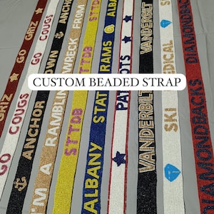 May include: A collection of custom beaded straps in various colors, each featuring text and designs. The straps include phrases like "Go Griz," "Cougs," and "Albany State." The text "Custom Beaded Strap" is also visible.
