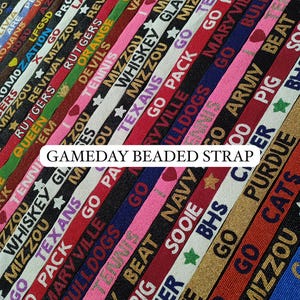 May include: A collection of beaded straps in various colors, each featuring team names and phrases like "GO PACK" and "MIZZOU." The text "GAMEDAY BEADED STRAP" is displayed prominently. These straps are likely for sports fans.
