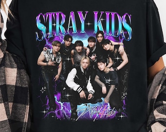 May include: Black t-shirt with a graphic of a group of people and the text "STRAY KIDS" in a retro font. The design incorporates a purple and blue lightning bolt effect.