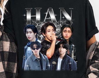 May include: Black t-shirt featuring a graphic of five people with the word "HAN" in a silver, lightning-bolt design. The people are in various poses, with a vintage, distressed aesthetic.