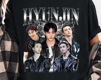 May include: Black t-shirt with a graphic of a group of people and the name "HYUNJIN" in a silver, distressed font. The design incorporates multiple images of the people. The t-shirt has a crew neck.