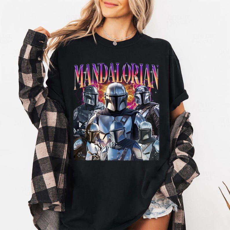 Pu&ograve; includere: T-shirt nera con una grafica di pi&ugrave; personaggi Mandaloriani in armatura. La parola "MANDALORIAN" &egrave; stampata in alto con un carattere retr&ograve; e colorato. Il design include vari modelli di elmetti e dettagli dell'armatura.