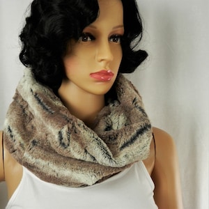 May include: A brown and gray faux fur infinity scarf. The scarf is soft and fluffy and would be a great addition to any winter wardrobe.