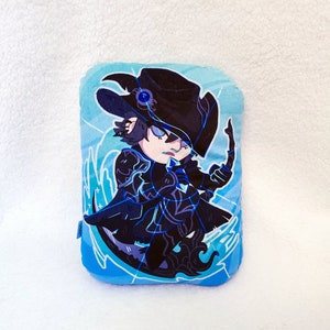 May include: A plush pillow featuring a cartoon character in a dark outfit with a hat and bow. The character is set against a blue and white background with a stylized design. The pillow is rectangular.