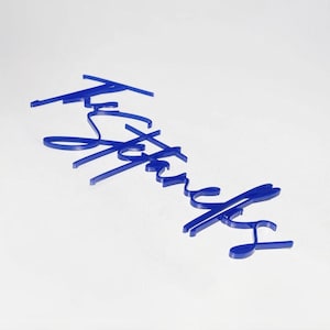 May include: A blue cursive word, "Father", is displayed against a white background. The word is made of a solid, dark blue material, with a slight shadow effect. The letters are connected in a flowing script style.