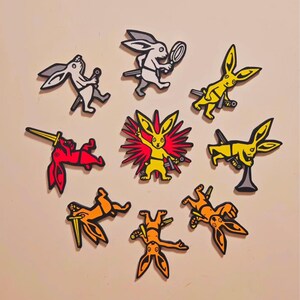 Könnte beinhalten: Eine Sammlung von Cartoon-Hasen-Aufklebern in verschiedenen Posen und Farben. Die Aufkleber zeigen Hasen in Weiß, Gelb, Rot und Orange, die jeweils eine Waffe oder einen Gegenstand halten. Einige Hasen sind schwarz umrandet, mit weißem Hintergrund.