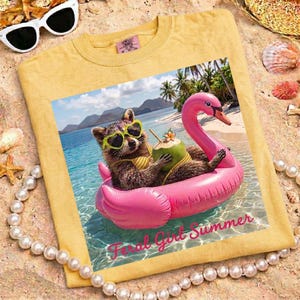 May include: Yellow t-shirt featuring a graphic of a raccoon wearing sunglasses and a bikini, floating on a pink flamingo in the ocean. The raccoon is holding a coconut drink. The text "Feral Girl Summer" is at the bottom.