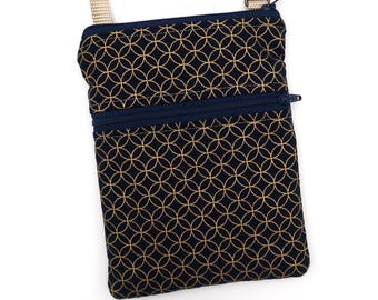 Puede incluir: Un bolso bandolera rectangular de tela azul marino oscuro con un patrón geométrico circular dorado repetitivo. El bolso incluye un cierre de cremallera superior, un bolsillo frontal horizontal con cremallera y una correa beige ajustable con un clip de metal bronce.
