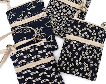 Puede incluir: Cuatro bolsos bandolera rectangulares de tela azul marino oscuro con patrones color crema de pájaros, bambú, libélulas y flores pequeñas. Cada bolso cuenta con un bolsillo frontal con cremallera y una correa beige ajustable.