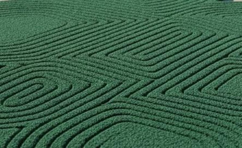 Puede incluir: Una alfombra de color verde bosque profundo con una superficie texturizada que presenta un patr&oacute;n repetitivo de l&iacute;neas rectangulares redondeadas conc&eacute;ntricas. El material parece ser un pelo denso y copetudo con relieve t&aacute;ctil.