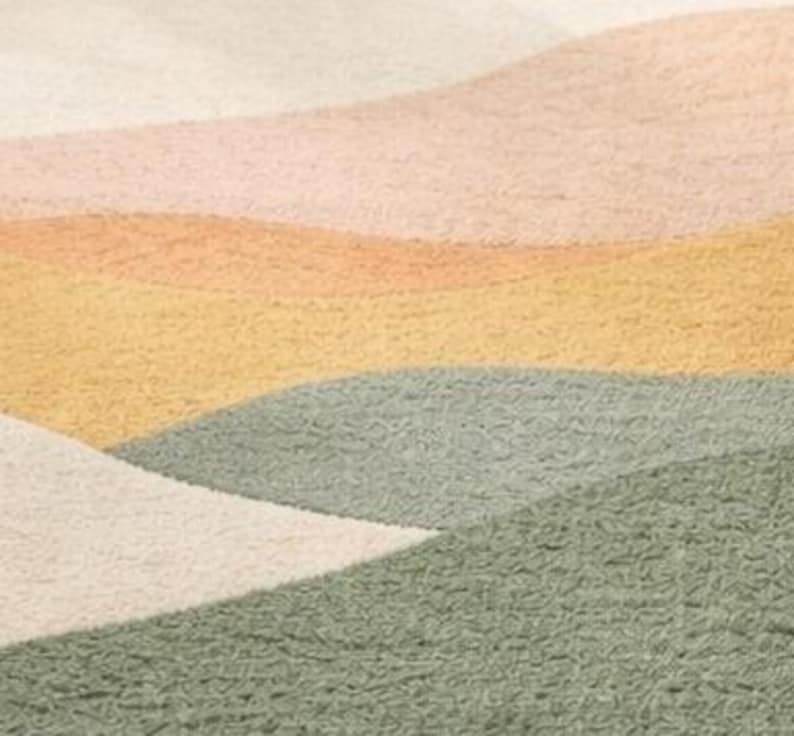 May include: A textured rug featuring a series of overlapping, curved, and wavy bands in shades of cream, soft peach, muted yellow, and sage green. The surface has a distinct, dense, and looped pile construction that creates a tactile, uneven appearance.