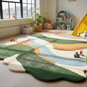 May include: A colorful, abstract rug with a mountain-like design. The rug features shades of green, blue, orange, and cream. The rug is placed on a light-colored wooden floor. A yellow teepee and a blue bookshelf are in the background.