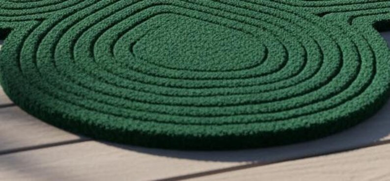 Puede incluir: Una alfombra de color verde oscuro con una superficie texturizada con formas conc&eacute;ntricas, redondeadas y org&aacute;nicas que crean un patr&oacute;n topogr&aacute;fico. La alfombra tiene una construcci&oacute;n de pelo grueso con surcos profundos.