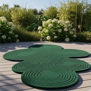 Puede incluir: Una alfombra de color verde oscuro con una superficie texturizada que presenta una serie de patrones circulares conc&eacute;ntricos. La alfombra tiene una forma org&aacute;nica irregular compuesta por varias secciones redondeadas superpuestas.