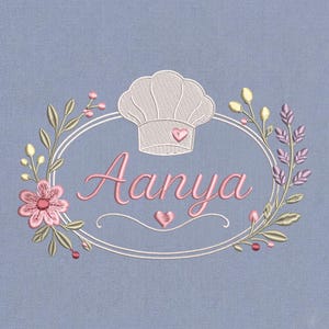 May include: Embroidered design on a light blue background. The design features the name "Aanya" in pink script, a chef's hat, and a floral wreath with pink and yellow accents. A heart is placed above and below the name.