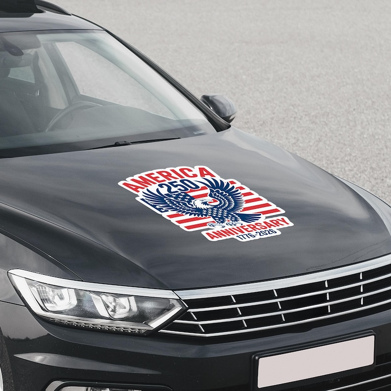 K&ouml;nnte beinhalten: Ein Aufkleber auf einer Motorhaube zeigt ein patriotisches Design zum 250. Jahrestag Amerikas. Der Aufkleber enth&auml;lt einen Wei&szlig;kopfseeadler, rot-wei&szlig;e Streifen und den Text "AMERICA 250 ANNIVERSARY 1776-2026" in Rot und Blau.