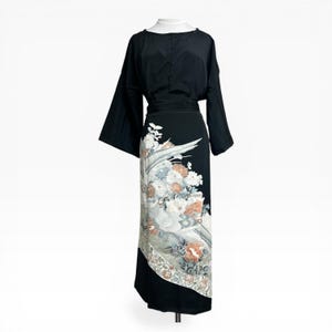 Puede incluir: Vestido negro con mangas largas y diseño floral. El vestido presenta un corpiño negro y una falda con un estampado floral blanco, gris y melocotón. El vestido se exhibe en un maniquí.