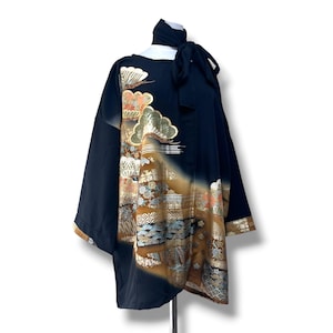 Puede incluir: Un kimono negro con un patrón decorativo con detalles dorados, marrones y azules. El kimono tiene mangas anchas y un lazo en el cuello. El diseño incluye elementos paisajísticos y se muestra sobre un fondo blanco.