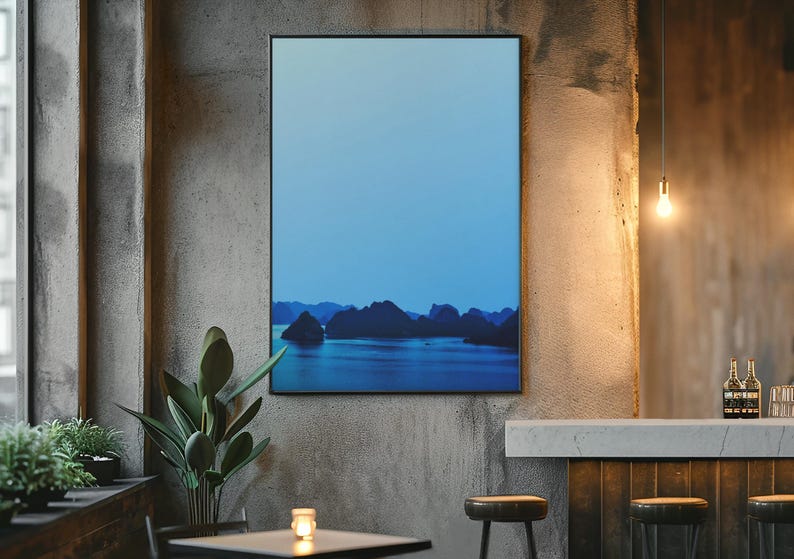 Blue-toned photograph of Ha Long Bay with coastal limestone islets reflected in calm water.