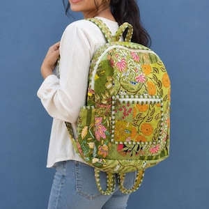 Può includere: Uno zaino trapuntato caratterizzato da un vivace design patchwork verde con motivi floreali e botanici nei toni dell'arancione, rosa e bianco. La borsa include una tasca frontale con cerniera, uno scomparto principale con cerniera bianca.