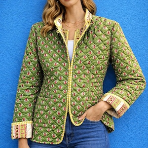 Può includere: Giacca trapuntata verde con motivo floreale rosso e bianco. La giacca ha finiture gialle e fodera bianca. I polsini e il colletto presentano una stampa decorativa. La giacca è indossata con jeans blu.