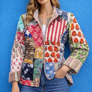Puede incluir: Una chaqueta patchwork con una variedad de patrones coloridos, incluyendo diseños florales, a rayas y de fresas. La chaqueta tiene cierre de cremallera y se usa con vaqueros azules. Las mangas están dobladas y el estilo es casual y bohemio.